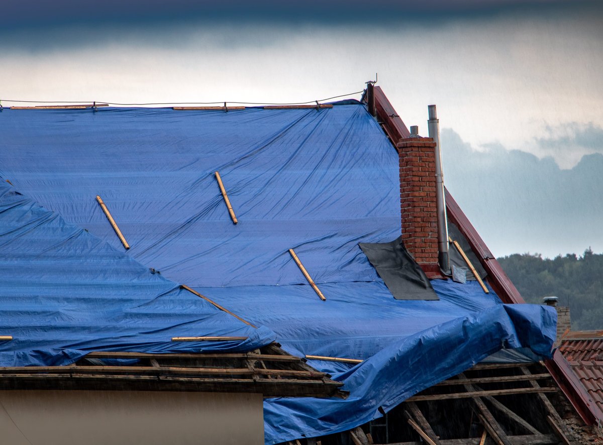 Roofer applying temporary waterproof covering during an emergency repair
